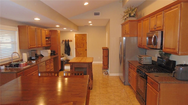 kitchen featuring light tile patterned floors, gas stove, lofted ceiling, dishwasher, and sink