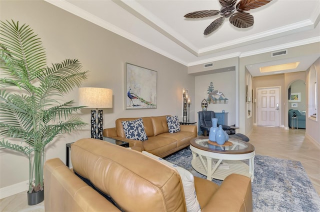 tiled living room with ceiling fan, a tray ceiling, and crown molding