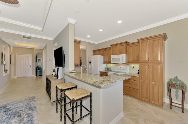 kitchen with light stone countertops, white appliances, a kitchen breakfast bar, kitchen peninsula, and crown molding