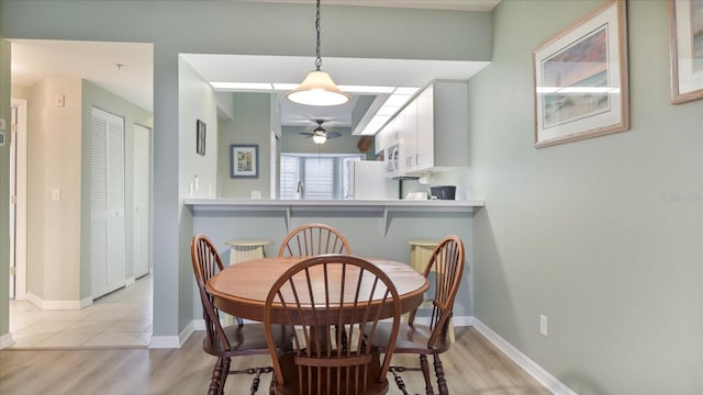 dining space with ceiling fan and light hardwood / wood-style flooring