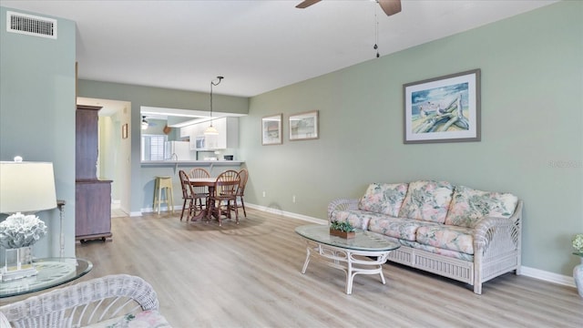 living room featuring ceiling fan and light hardwood / wood-style flooring