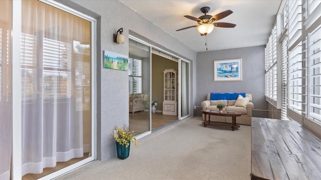 living area featuring ceiling fan, carpet flooring, and a healthy amount of sunlight