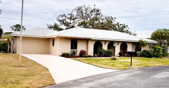 ranch-style house featuring a garage and a front lawn