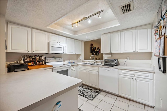 kitchen featuring sink, white appliances, a tray ceiling, and white cabinets