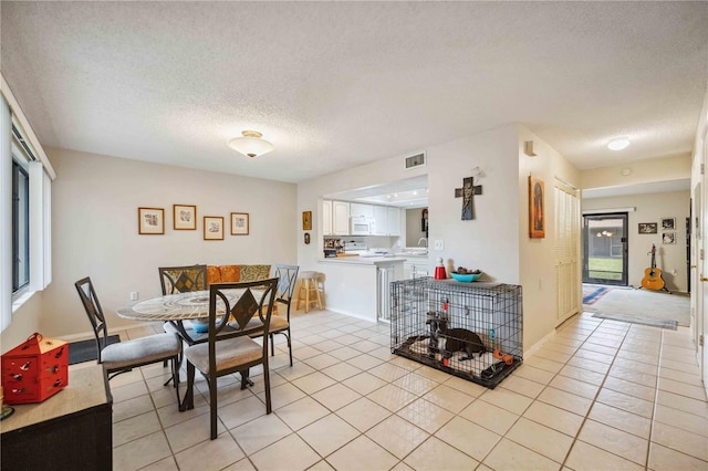 tiled dining area featuring plenty of natural light and a textured ceiling