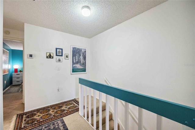 hall featuring a textured ceiling and carpet floors