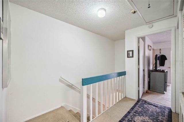 hallway with a textured ceiling and carpet flooring