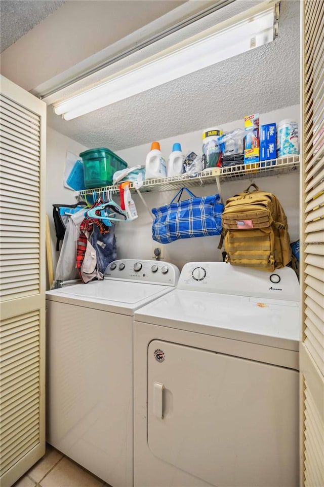 washroom featuring a textured ceiling, independent washer and dryer, and light tile patterned flooring