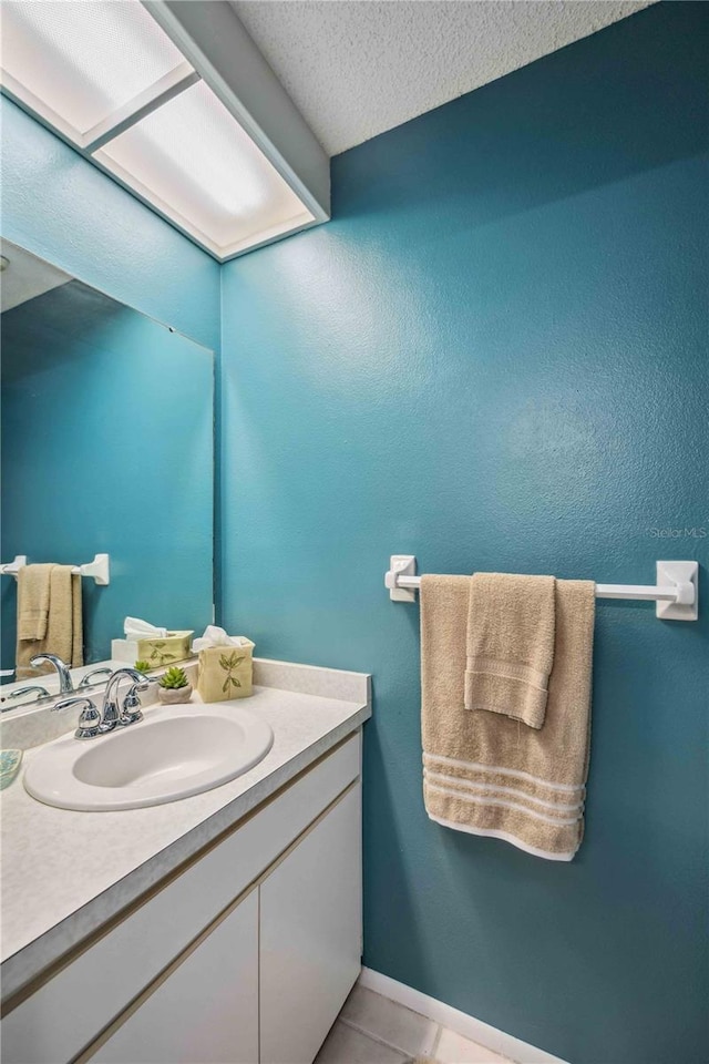 bathroom with a textured ceiling, tile patterned floors, and vanity