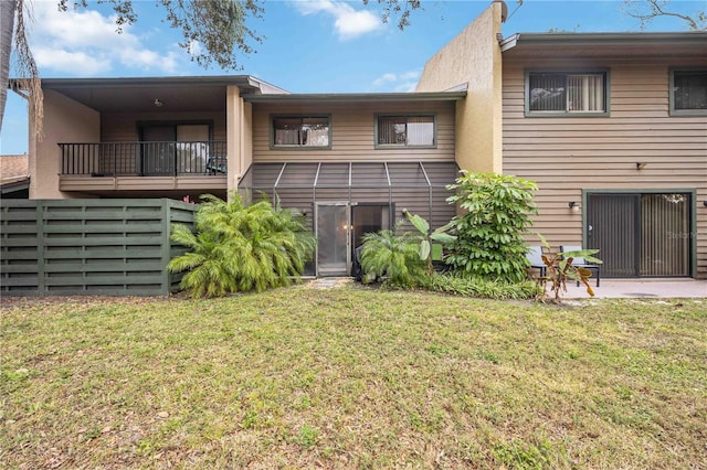 back of property with a balcony and a lawn