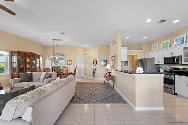 living room with ceiling fan with notable chandelier and light tile patterned flooring