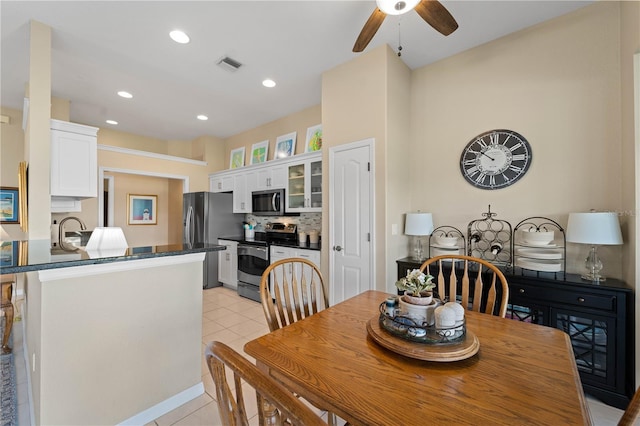 tiled dining room with ceiling fan and sink