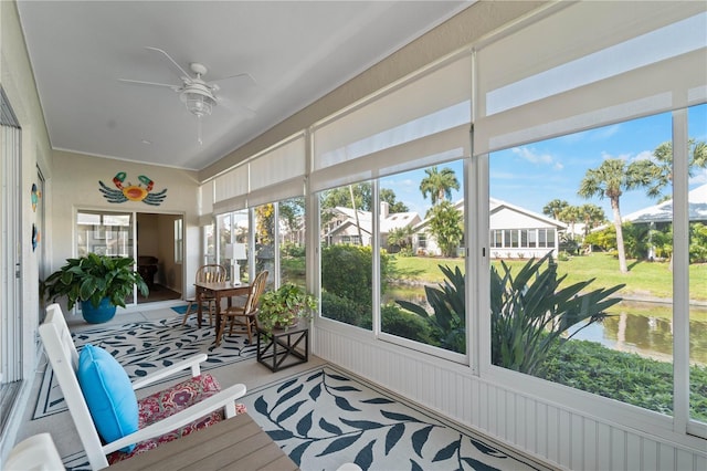 sunroom / solarium featuring ceiling fan and a water view