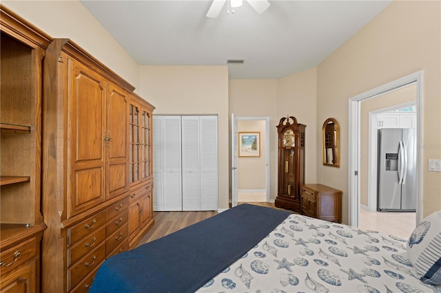 bedroom featuring stainless steel fridge with ice dispenser, ceiling fan, a closet, and wood-type flooring