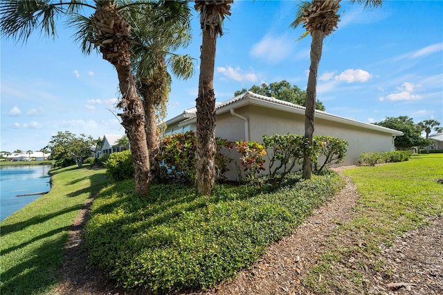 view of side of home with a water view and a yard