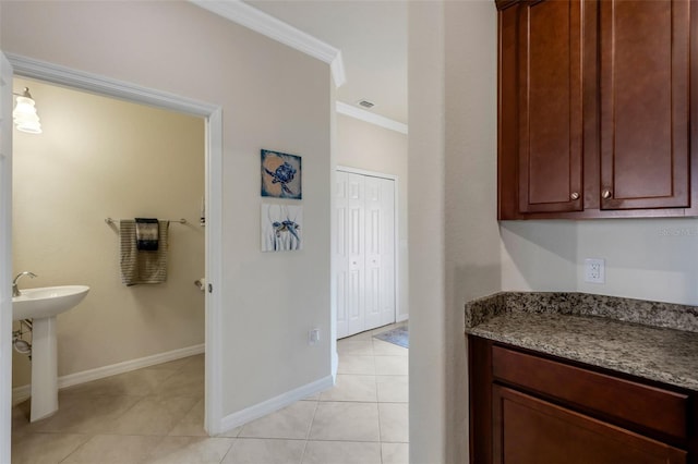 kitchen with stone counters, ornamental molding, and light tile patterned floors