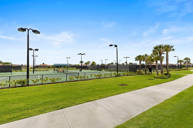 view of community with tennis court and a lawn