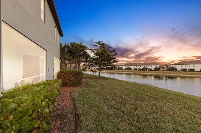 yard at dusk featuring a water view