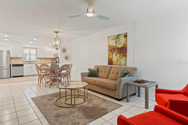 living room featuring sink, light tile patterned flooring, and ceiling fan with notable chandelier