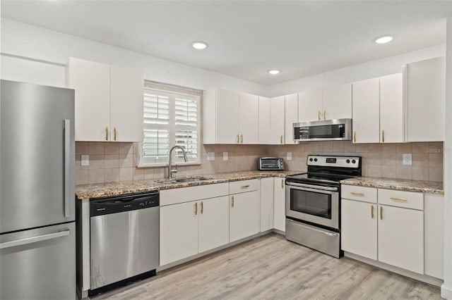 kitchen featuring light stone counters, sink, white cabinetry, and appliances with stainless steel finishes