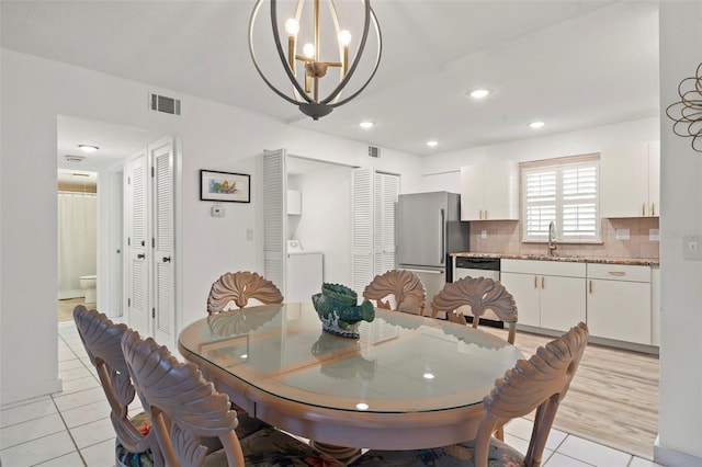 tiled dining area featuring a chandelier, washer / clothes dryer, and sink