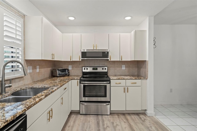 kitchen with tasteful backsplash, appliances with stainless steel finishes, sink, and white cabinetry