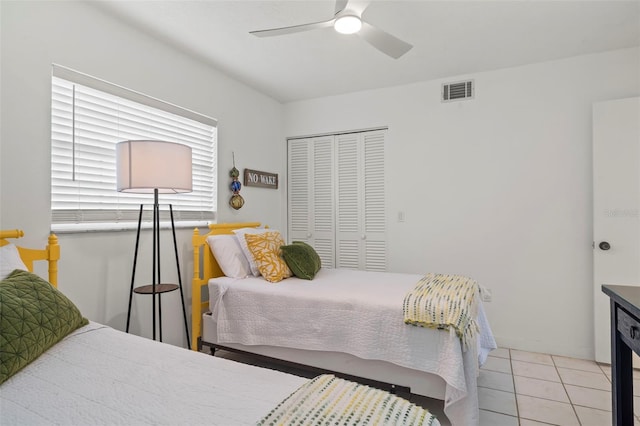 bedroom featuring ceiling fan, light tile patterned floors, and a closet