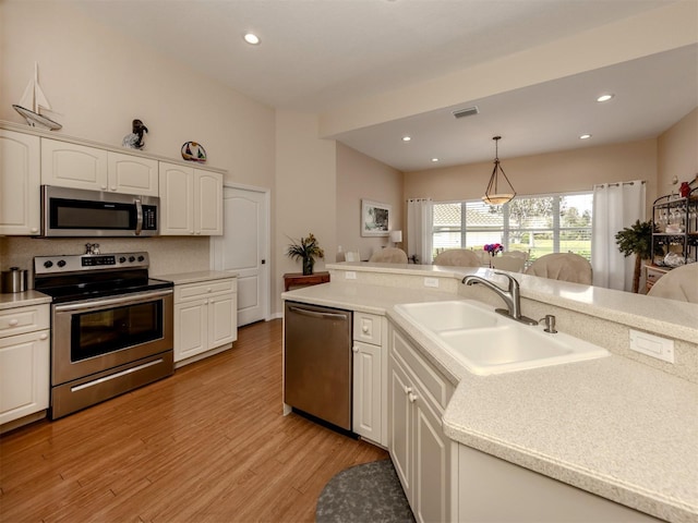 kitchen featuring pendant lighting, appliances with stainless steel finishes, sink, white cabinetry, and light hardwood / wood-style floors