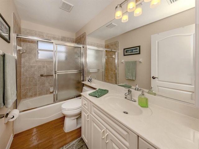 full bathroom featuring vanity, toilet, combined bath / shower with glass door, and wood-type flooring