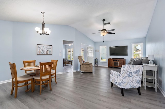 dining room with hardwood / wood-style flooring, vaulted ceiling, and ceiling fan with notable chandelier