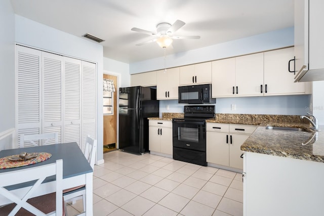 kitchen with sink, light tile patterned floors, black appliances, white cabinets, and dark stone counters