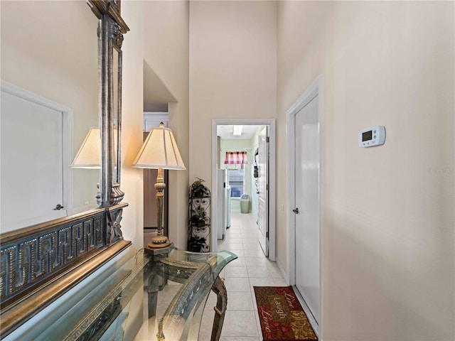 hall featuring light tile patterned floors and a high ceiling