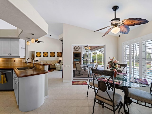 dining room with sink, light tile patterned floors, and vaulted ceiling