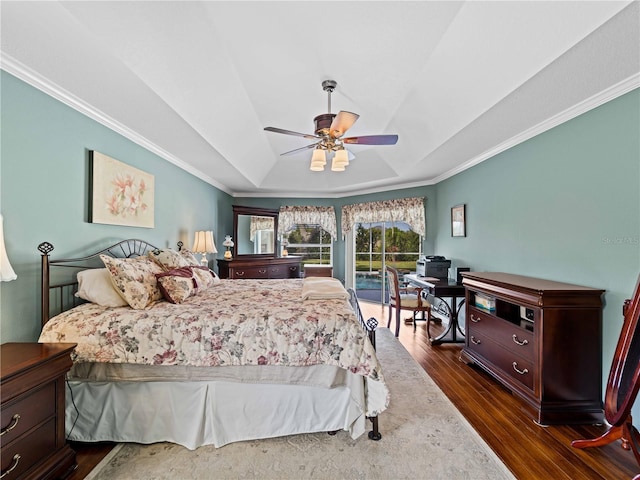 bedroom featuring ceiling fan, dark hardwood / wood-style flooring, ornamental molding, and a tray ceiling