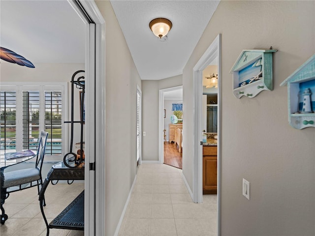 corridor featuring a textured ceiling and light tile patterned floors