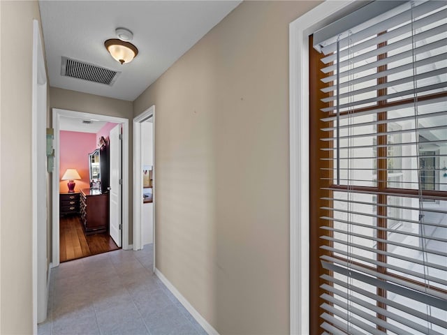 corridor featuring light tile patterned floors and plenty of natural light