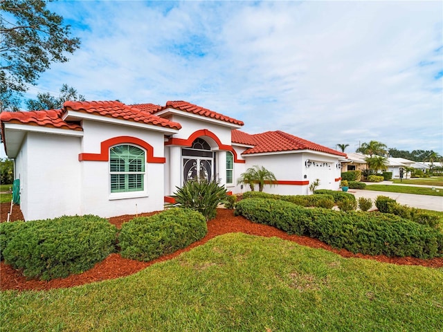 mediterranean / spanish home with a front yard and a garage