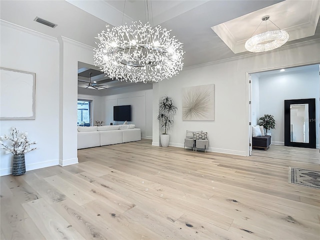 living room with crown molding, a chandelier, a raised ceiling, and light wood-type flooring