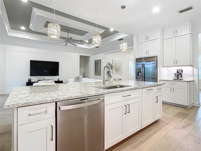 kitchen with white cabinetry, stainless steel appliances, decorative light fixtures, and sink