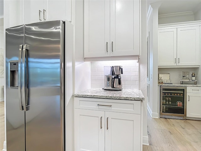 kitchen with stainless steel refrigerator with ice dispenser, white cabinetry, light stone counters, beverage cooler, and decorative backsplash