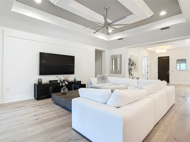 living room featuring a raised ceiling, crown molding, ceiling fan, and light hardwood / wood-style floors