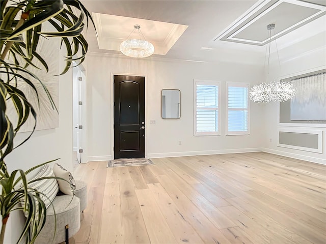 foyer entrance with a tray ceiling, ornamental molding, and light wood-type flooring