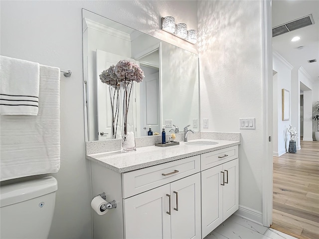 bathroom with vanity, ornamental molding, and toilet