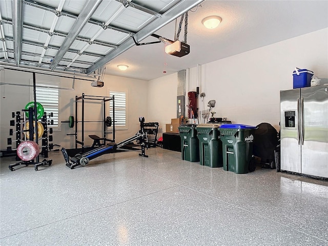 garage featuring stainless steel refrigerator with ice dispenser, a garage door opener, and electric panel