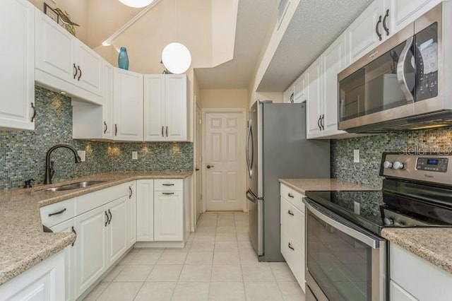 kitchen featuring decorative light fixtures, white cabinetry, appliances with stainless steel finishes, and light tile patterned flooring