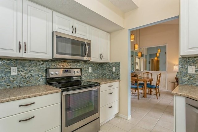 kitchen with white cabinets, backsplash, light tile patterned floors, and appliances with stainless steel finishes