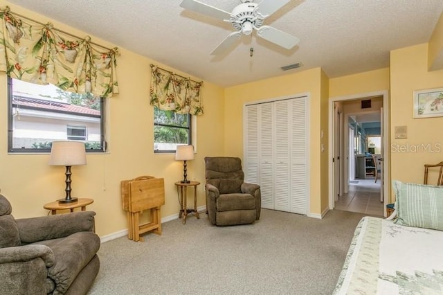 sitting room featuring a textured ceiling, light colored carpet, and ceiling fan