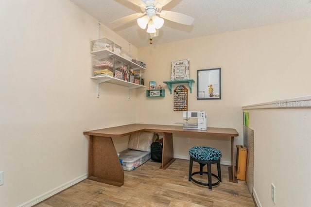 office with wood-type flooring, ceiling fan, and built in desk