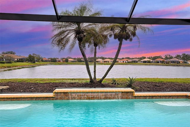 pool at dusk with pool water feature and a water view