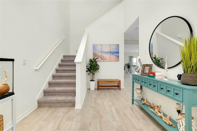 entryway with a towering ceiling and light hardwood / wood-style flooring